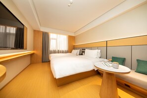A hotel room with a large bed, bedside table, and a small round table with a cup and saucer. - Ji Hotel (Xi'an)