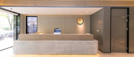 A reception desk with a digital screen, a wall-mounted sign, and a door.