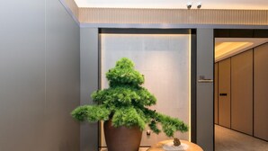 A modern interior with a large potted plant, a wooden sculpture, and a sliding door. - Ji Hotel (Shanghai)