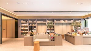 A modern hotel lobby with a reception desk, seating area, and book-lined shelves. - Ji Hotel (Shanghai)