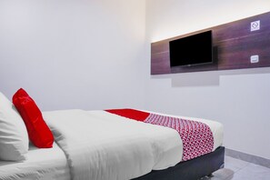 Una habitación de hotel moderna con una cama, un televisor montado y un panel de control en la pared.