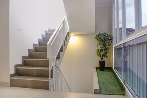 Eine Treppe mit weißer Geländer, einer Topfpflanze und einem kleinen Bereich aus Kunstgrün.