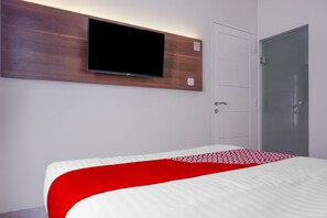A hotel room with a bed, a mounted TV, a wardrobe, and a door. - Super OYO 90115 Near Pasar Baru (Jakarta)