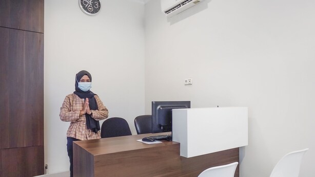 A reception desk with a computer, chairs, and a clock on the wall. - Super OYO 90115 Near Pasar Baru (Jakarta)