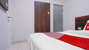 A hotel room with a bed, a wardrobe, and a door. - Super OYO 90115 Near Pasar Baru (Jakarta)