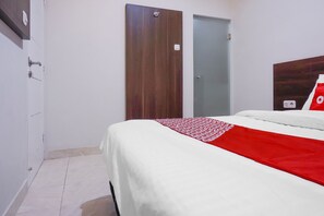 Een hotelkamer met een bed, een kledingkast en een deur.