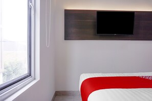 A hotel room with a bed, a window, and a mounted television. - Super OYO 90115 Near Pasar Baru (Jakarta)