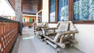 A corridor with a tiled floor, wooden benches, and a view of a building with green doors.