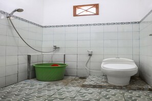 Un baño pequeño con inodoro, ducha y un cubo verde.