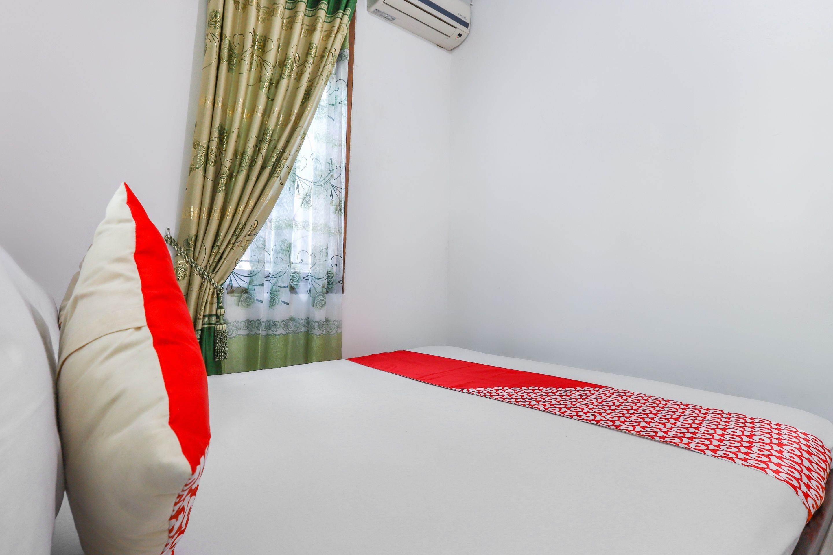 Une chambre avec un lit, un oreiller, une fenêtre avec des rideaux et un appareil de climatisation.