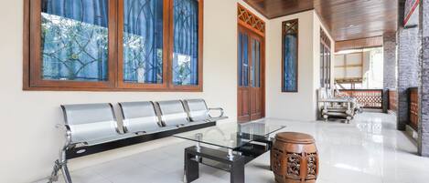 Un interior moderno con una mesa de vidrio, un banco de metal y un taburete de madera tradicional.