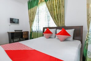 A hotel room with a bed, a desk, and a TV.