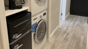 A compact laundry area with a Bosch washing machine, a coffee maker, and a refrigerator.
