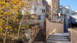 A building with a unique curved tower, a staircase leading to a lower level, and a pathway with scattered leaves.