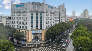 A multi-story hotel with a prominent sign, a corner location, and a busy street with traffic. - Hanting Hotel Taizhou Jiaojiang Baolong City (Taizhou)