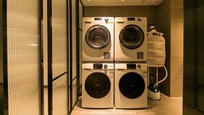 A laundry area with two stacked front-loading washing machines and a stacked dryer. - Hanting Hotel Taizhou Jiaojiang Baolong City (Taizhou)