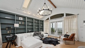 Ein geräumiges Wohnzimmer mit einem Ecksofa, einem Ledersessel und einem großen Fenster mit Blick.