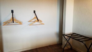 A room with two wooden hangers on the wall and a black metal folding chair.