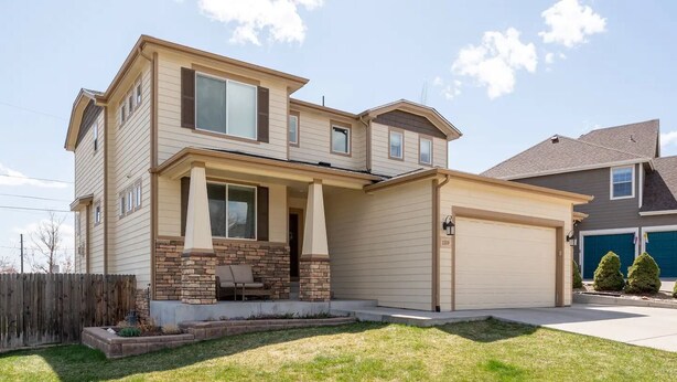A two-story house with a front porch, a garage, and a well-maintained lawn.