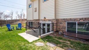 A house with a stone accent wall, a covered patio with two blue Adirondack chairs, and a screened-in area with a window.
