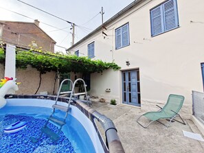 A swimming pool with a ladder, a chair, and a small inflatable unicorn decoration.