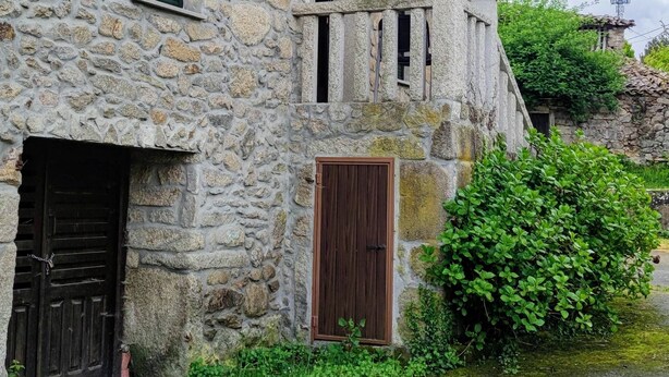 Un bâtiment en pierre avec une porte en bois et une petite fenêtre.