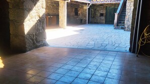 Une cour entourée de murs en pierre, avec un sol carrelé, une porte en bois et un câble jaune.