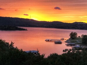 A sunset over a lake with a dock and a small building.