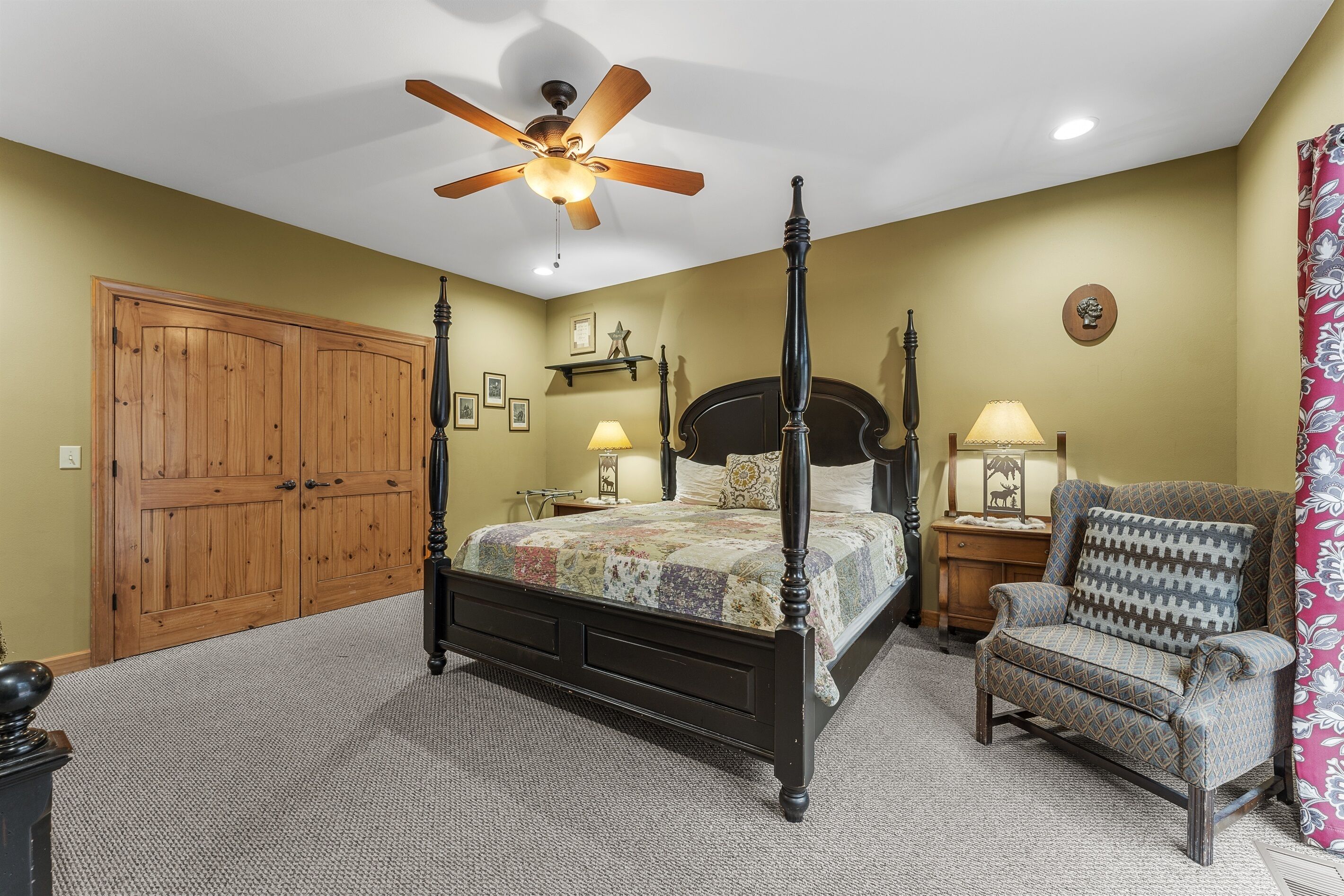 Une chambre à coucher avec un lit à baldaquin, une chaise, un ventilateur de plafond et une armoire en bois.