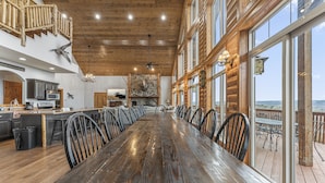 A spacious wooden dining area with a long table, chairs, and a view of the outdoors. - Beautiful Views from the Rusty Moose (Branson West)