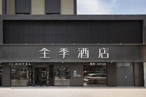 A hotel entrance with a modern facade, large glass doors, and signage indicating a KETING section.