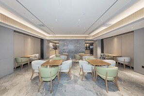 A modern hotel lobby with marble flooring, wooden tables, and green chairs. - Ji Hotel Beijing Jiuxianqiao 798 Art District (Beijing)