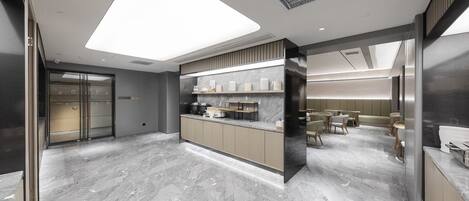 A modern hotel lobby with a marble floor, a reception desk, and a seating area with tables and chairs.