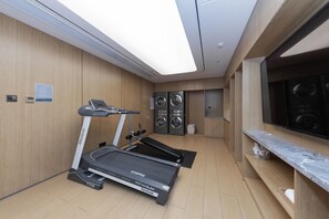 A modern gym with a treadmill, stationary bike, and two wall-mounted washing machines. - Ji Hotel Beijing Jiuxianqiao 798 Art District (Beijing)