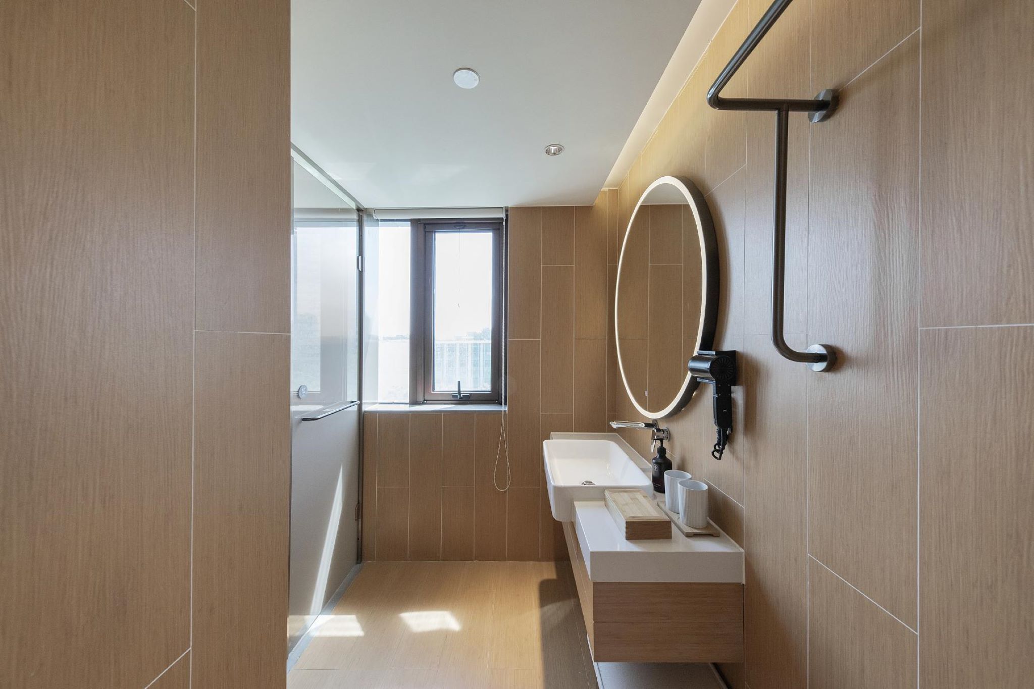 A modern bathroom with a large mirror, a sink, and a window.