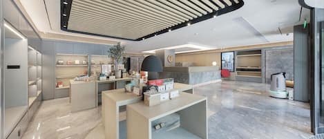 A modern hotel lobby with a central reception desk, seating areas, and a large digital display.