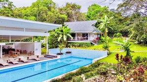 Ein modernes Haus mit Pool, Sitzgelegenheiten im Freien und üppiger Bepflanzung.