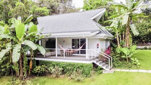 Ein Haus mit überdachter Veranda, einer Hängematte und einer Treppe zum Eingang.