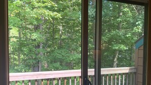 A balcony with a wooden railing overlooking a forested area.