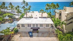 A hotel with a flat roof, a parking lot, and a view of the ocean. - OCEANFRONT; Stunning Corner Unit in Quiet Boutique Complex, Spacious, Pool, A/C! (Kailua-Kona)