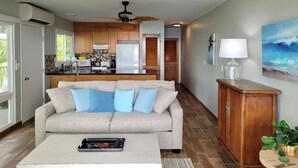 A modern living room with a beige sofa, a coffee table, and a wooden cabinet. - OCEANFRONT; Stunning Corner Unit in Quiet Boutique Complex, Spacious, Pool, A/C! (Kailua-Kona)