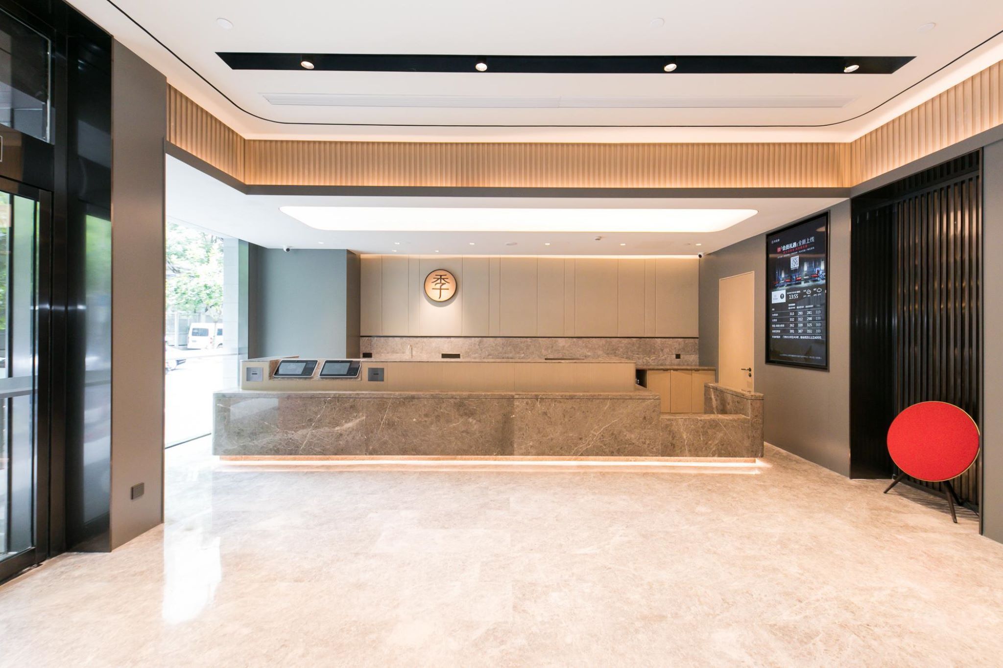 A modern reception area with a marble counter, a digital display, and a wooden accent wall.