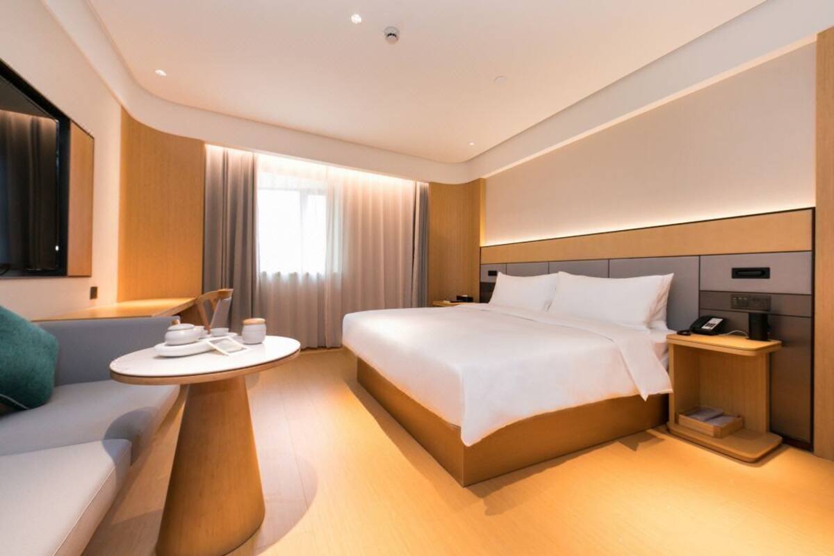 A modern hotel room with a bed, bedside table, and a small seating area with a table.