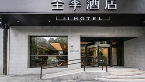 A hotel entrance with a modern design, featuring a prominent sign with Chinese characters and the word 'HOTEL' in English.