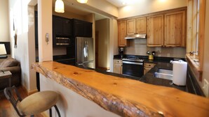 Una cocina con gabinetes de madera, electrodomésticos de acero inoxidable y encimera de madera.