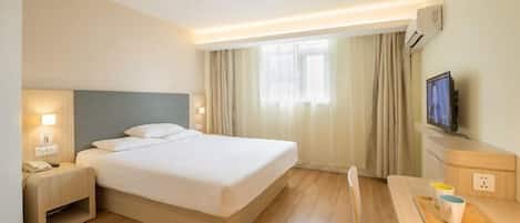 Una habitación de hotel con cama, mesita de noche, televisión y un escritorio con silla.