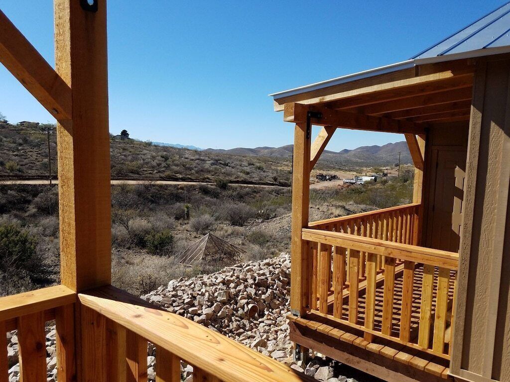 A wooden deck with a railing overlooking a desert landscape.