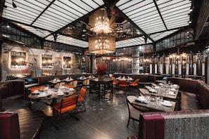 A spacious restaurant with high ceilings, large windows, and a variety of seating arrangements including booths and tables. - Paradox Vancouver (Vancouver)