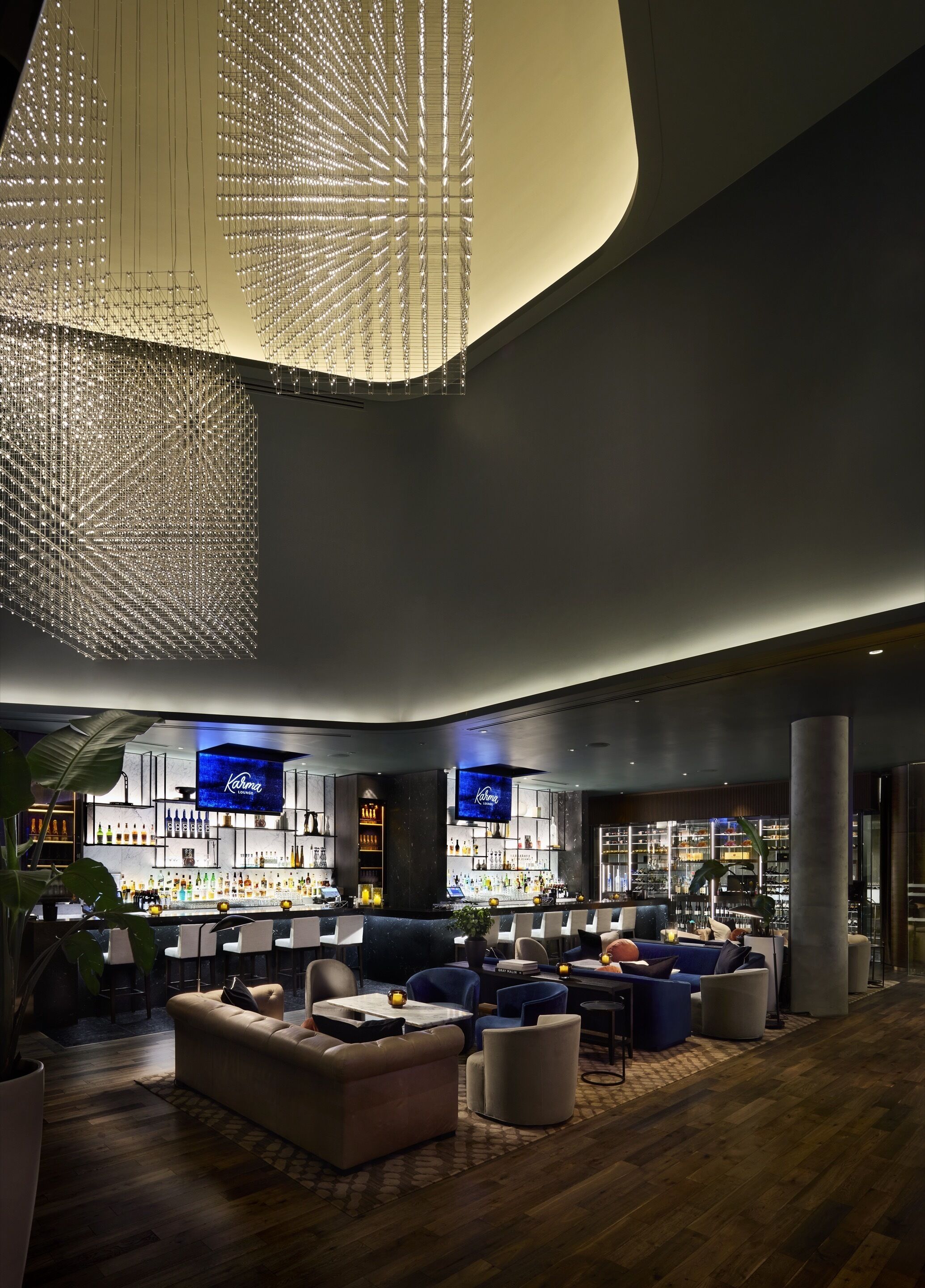 A modern bar area with a curved ceiling, bar counters, seating, and a large digital screen displaying the brand name.