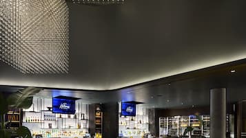 A modern bar area with a curved ceiling, bar counters, seating, and a large digital screen displaying the brand name.